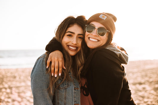 Two women on the beach, smiling at the camera