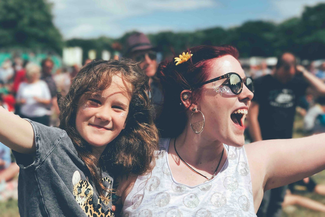 A woman and a young person are outside standing in a field. The woman cheers at something off-camera