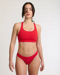 Front view of a woman with her arms at her sides, she is wearing a red thong period panty and a red sports bra | Raspberry